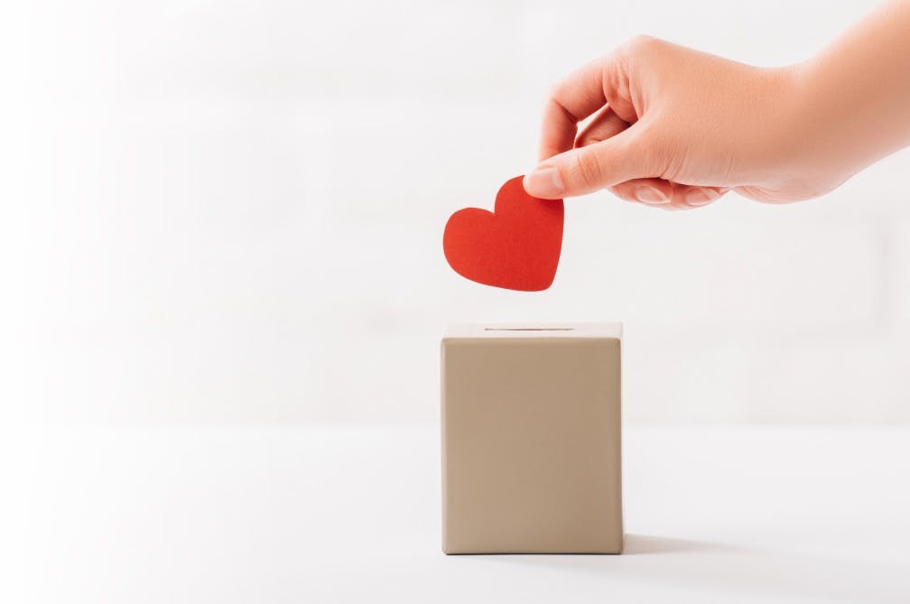 Photo of a hand placing a heart-shaped cutout into a box