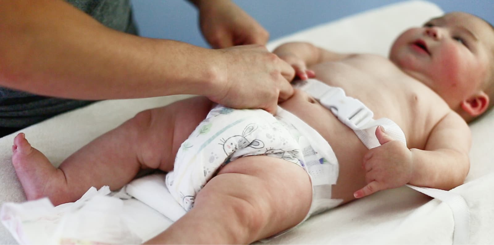 Background. Baby being strapped into a diaper changing station.